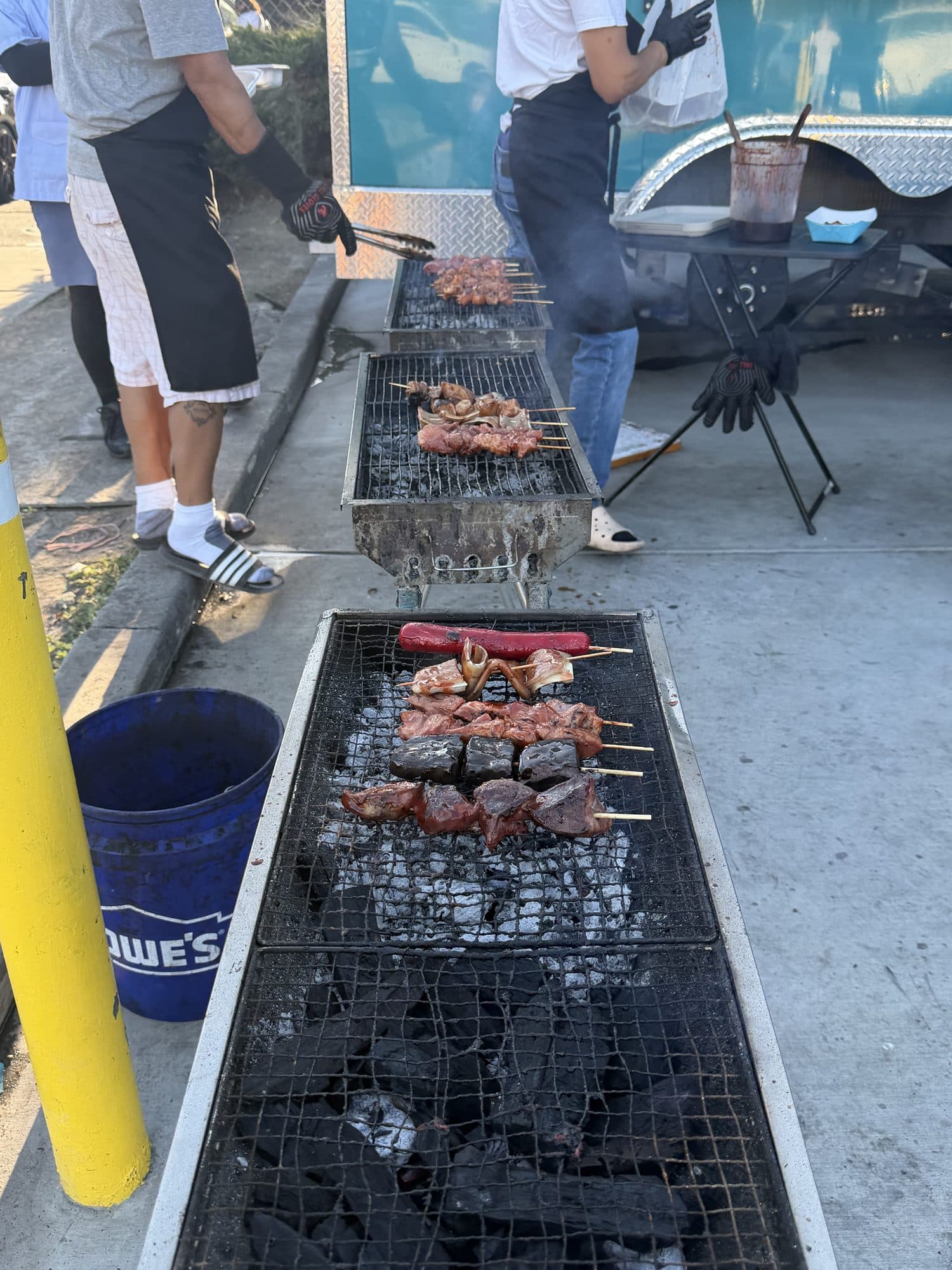 Three grills in a row with the team working the skewers